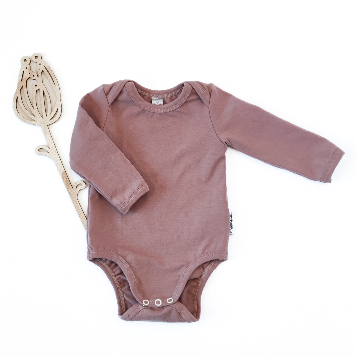 Vorderansicht eines Babybodys mit amerikanischem Ausschnitt in der Farbe rosa neben Holdeko