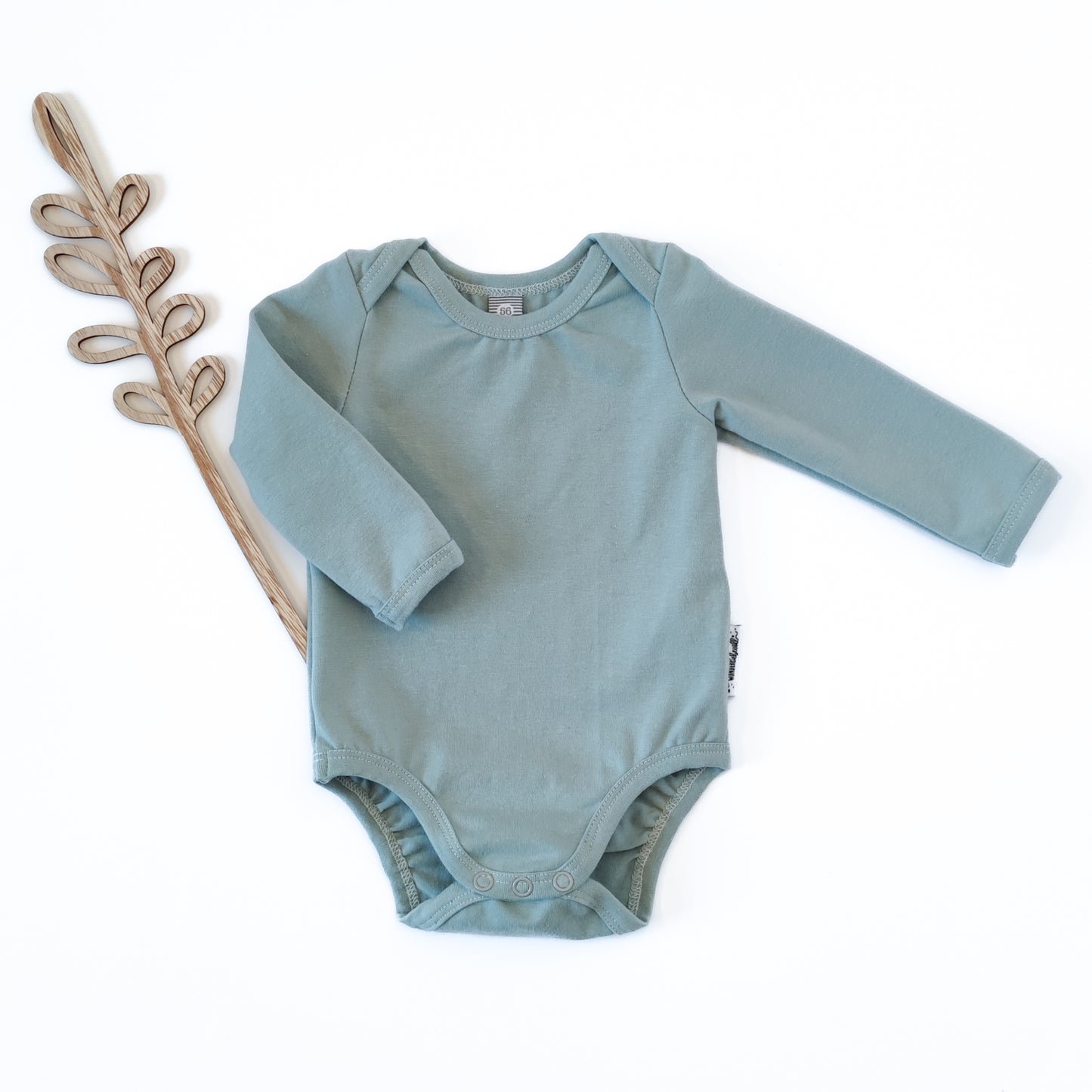 Vorderansicht eines Babybodys mit amerikanischem Ausschnitt in der Farbe blau neben Holdeko