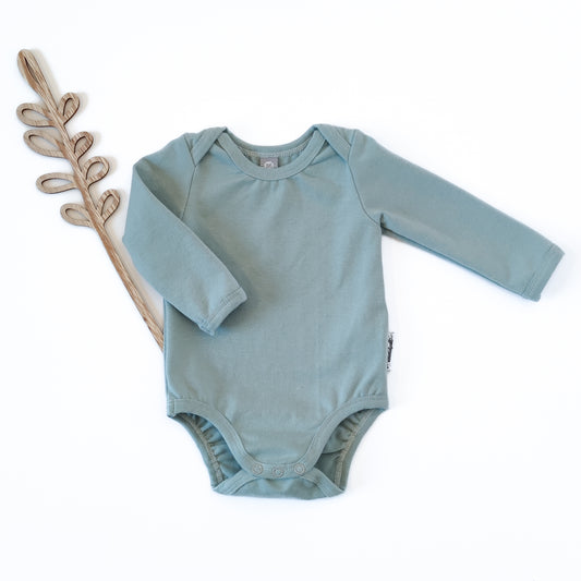 Vorderansicht eines Babybodys mit amerikanischem Ausschnitt in der Farbe blau neben Holdeko